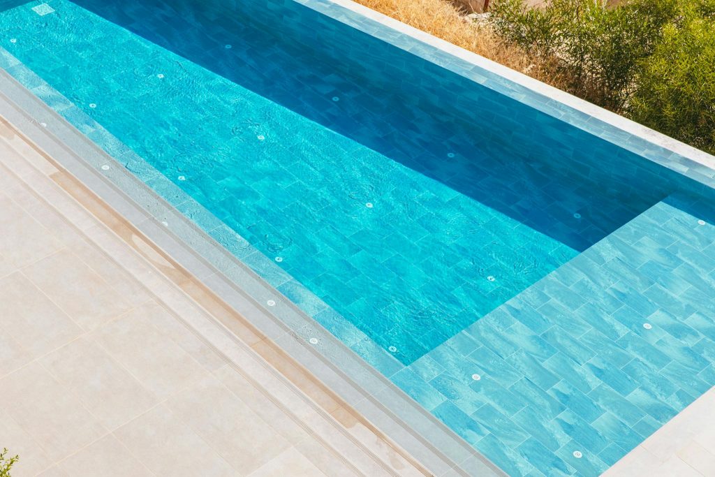 Elegant aerial view of a luxurious swimming pool surrounded by a serene deck. Perfect for summer themes.